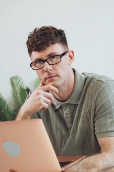 椅子に座って手に持ってノートパソコンを使うカメラ目線の男性 男性,外国人,欧米人の写真素材