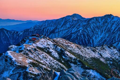冠雪の夕焼けの北アルプスの燕山荘と常念岳 冠雪,雪山,冬山の写真素材