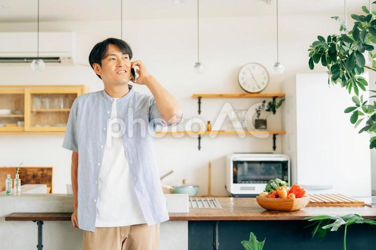 家でスマホを使う男性（通話・笑顔） 電話,スマホ,男性の写真素材