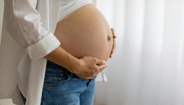 白いシャツを着た日本人妊婦の臨月のお腹 白いシャツを着た日本人妊婦の臨月のお腹の写真