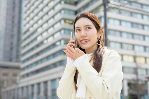 ビル街で電話をする女性 ビル街で電話をする女性 スマホ,元気,キャリアウーマンの写真素材