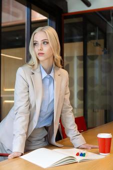 テーブルに手をついて立っている真剣な表情のビジネスウーマンの写真