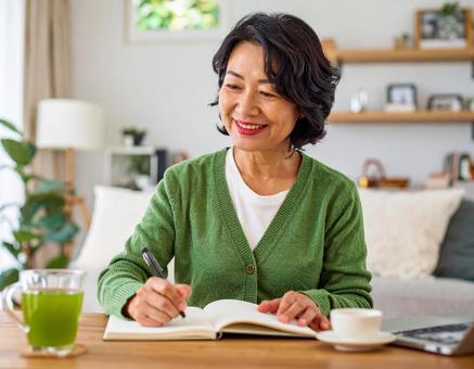 テキストを開きノートに書く日本人女性 テキストを開きノートに書く日本人女性の写真