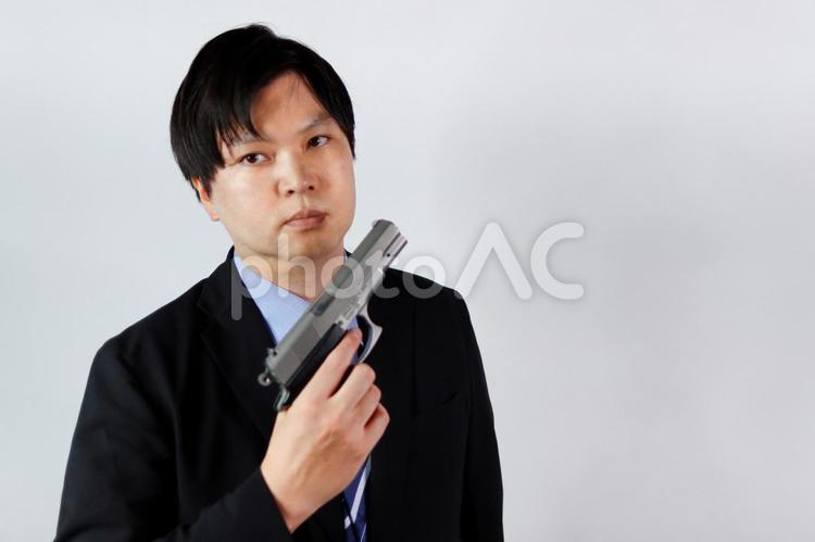 スーツ姿の男性とピストル 男性,ピストル,銃の写真素材