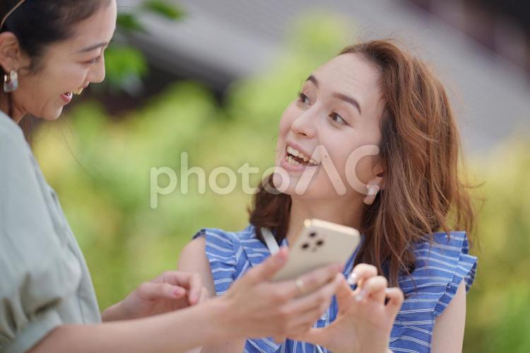 公園でスマートフォンを見ている2人の女性 女子旅,女性,日本人の写真素材