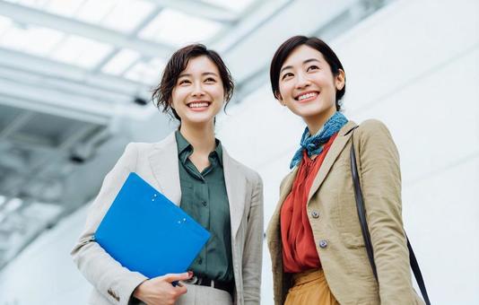 会社で笑顔で会話する二人の女性 会社で笑顔で会話する二人の女性の写真