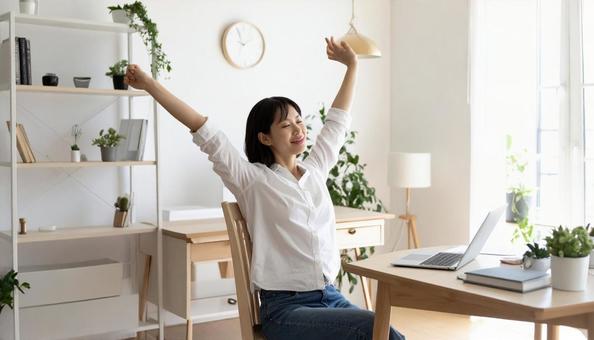 伸びをする30代のフリーランスの女性の写真