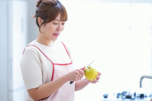 キッチンで皮むきをする女性 女性,リンゴ,皮むきの写真素材