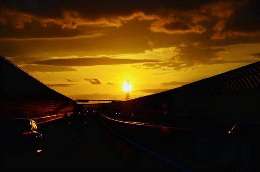 夕暮れに染まる高速道路と沈む夕日 夕暮れに染まる高速道路と沈む夕日の写真
