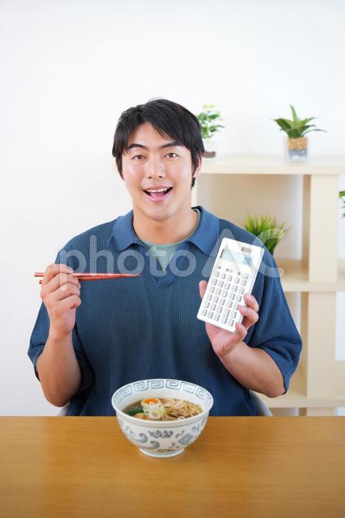電卓を持ちラーメンを食べる男性 男性,電卓,持つの写真素材