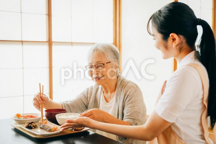 食事をする高齢者女性と女性スタッフ（笑顔） 高齢者,おばあちゃん,食事の写真素材