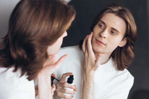 鏡を見ながら乳液を塗っている若い男性 男性,外国人,欧米人の写真素材