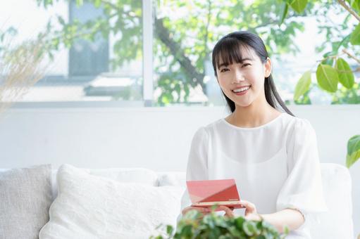 リビングで貯金通帳を見る若い女性 リビングで貯金通帳を見る若い女性の写真