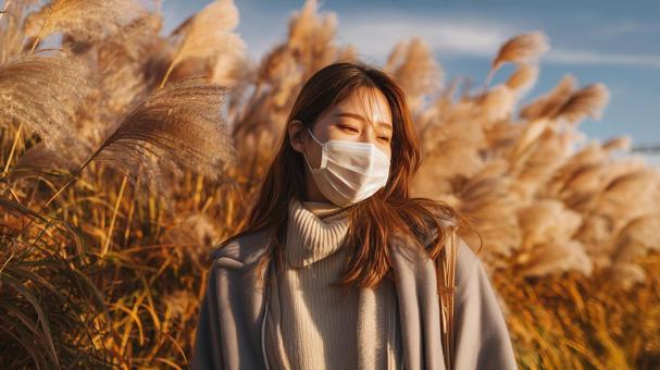 秋風に揺れるススキとマスク姿の女性 秋風に揺れるススキとマスク姿の女性の写真
