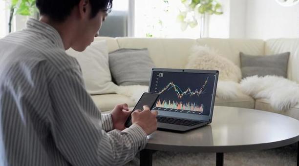 株価の上昇を見て喜ぶアジア人男性 株価,上昇,喜ぶの写真素材