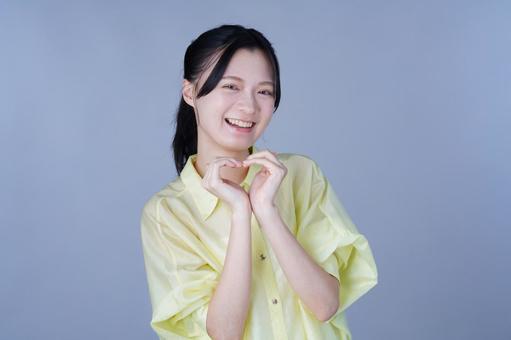 指ハートを作る黄色い服の女性 女性,ハート,ポーズの写真素材