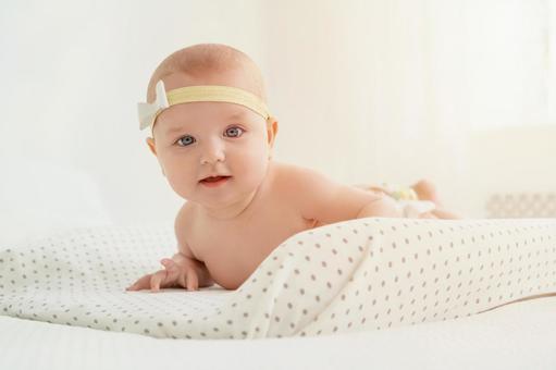リボンのヘアバンドをしている外国人赤ちゃん リボンのヘアバンドをしている外国人赤ちゃん 赤ちゃん,腹ばい,うつ伏せの写真素材