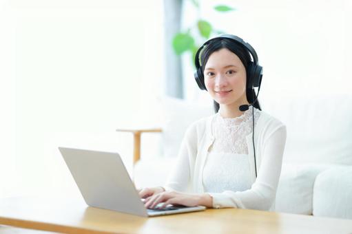 ヘッドセットでパソコンをするカメラ目線の女性 女性,ノートパソコン,微笑むの写真素材