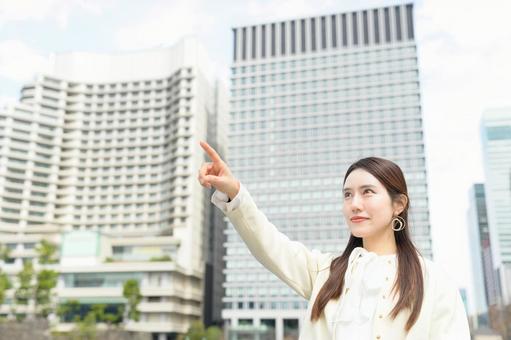 ビル街で遠くを指をさす女性 ビル街で遠くを指をさす女性 指差し,キャリアウーマン,ビジネスの写真素材