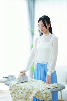 窓際でアイロン掛けをする女性 女性,アイロン,アイロン台の写真素材
