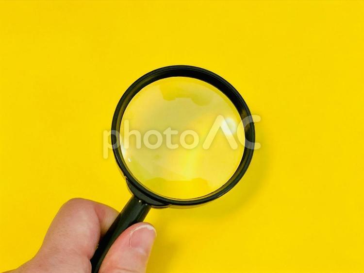 虫眼鏡を持つ手元（イエロー背景） 虫眼鏡,チェック,確認の写真素材