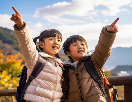 紅葉に染まる山で空をさす子供たち 紅葉に染まる山で空をさす子供たちの写真