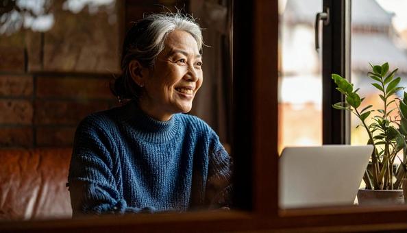 パソコンに向かって笑顔の50代の女性 パソコンに向かって笑顔の50代の女性の写真