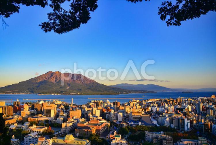 城山より夕景に染まる鹿児島の街と桜島を眺める　左寄せ オレンジ,城山,夕方の写真素材