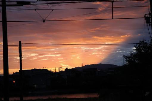 茜色の夕空とシルエットの山と街の風景 茜色の夕空とシルエットの山と街の風景の写真