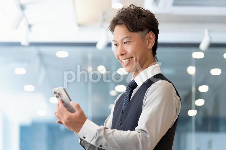 スマホの画面を見る笑顔の男性ビジネスマン 男性,スマホ,スマートフォンの写真素材