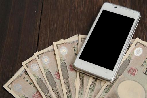 スマホと一万円札のイメージ スマホと一万円札のイメージの写真