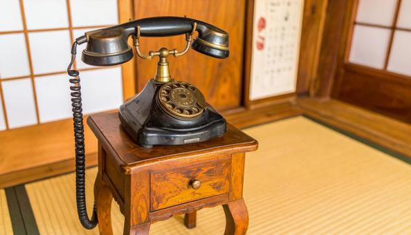 電話台の上に置いてある昔ながらの黒電話 電話台の上に置いてある昔ながらの黒電話の写真