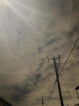 電柱と曇り空の中に日差しがある風景 電柱,日差し,くもり空の写真素材