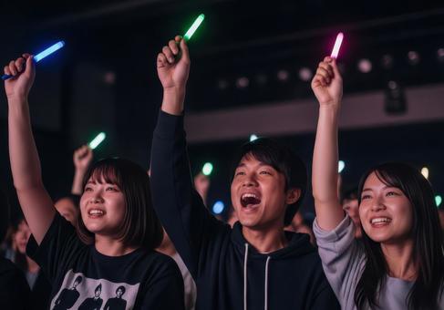 ライブでペンライトを振る男女の姿の写真