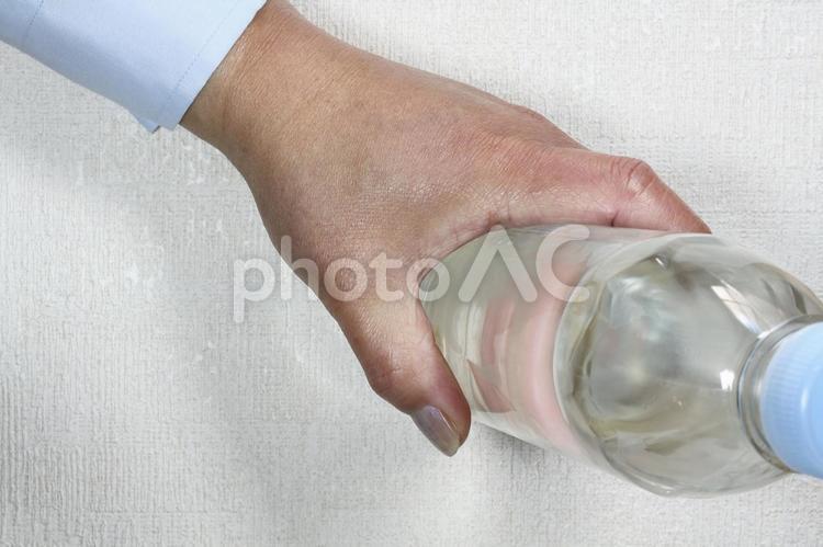 水が入ったペットボトルを持つ男性の手元 水,ペットボトル,手元の写真素材