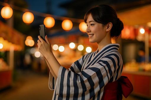 スマホで撮影する浴衣女性 スマホで撮影する浴衣女性の写真