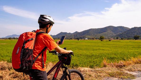 自転車を止めてスマホを見る男の子 自転車を止めてスマホを見る男の子の写真