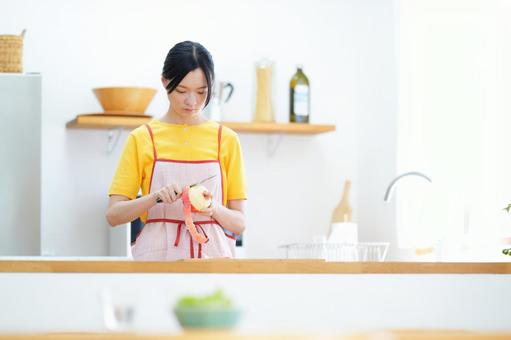 真剣な顔で皮むきをしているキッチンの女性の写真