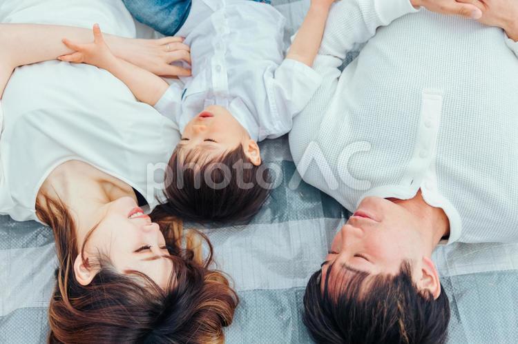 レジャーシートの上で寝る親子（3人） 親子,お昼寝,レジャーシートの写真素材
