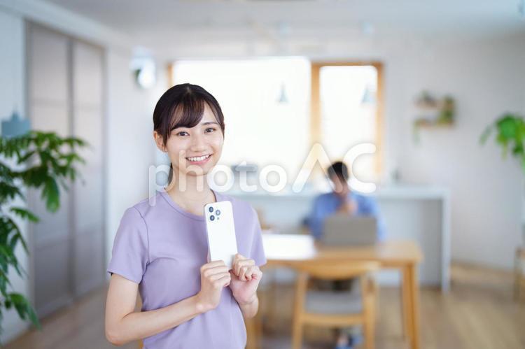 カメラ目線でスマホを持つ笑顔の女性 女性,スマートフォン,持つの写真素材