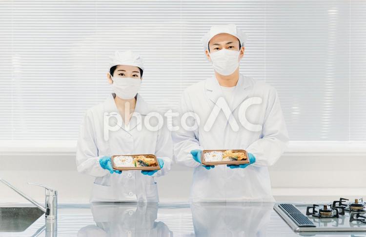 お弁当の盛り付けをする男女（食品加工） 食品工場,給食,社員食堂の写真素材