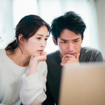 パソコンを見つめて悩む男女 パソコンを見つめて悩む男女の写真