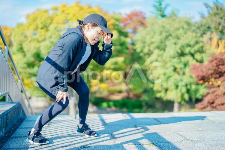 汗を拭くスポーツウェアを着た女性（疲労） 疲労,息切れ,運動の写真素材