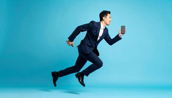 携帯電話を持って走るビジネスマン 携帯電話を持って走るビジネスマンの写真