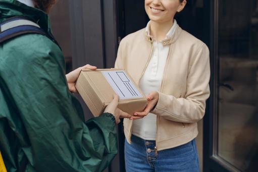 配達員から配達物を受け取る笑顔の女性 配達,デリバリー,配送の写真素材