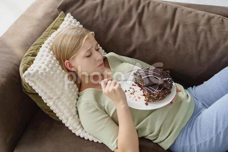 寝転んでケーキ絵を食べる女性 女性,人物,見るの写真素材