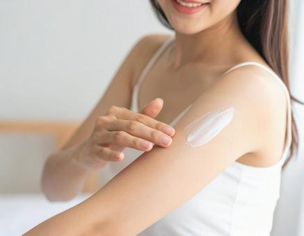 腕に日焼け止めクリームを塗る女性 腕に日焼け止めクリームを塗る女性の写真