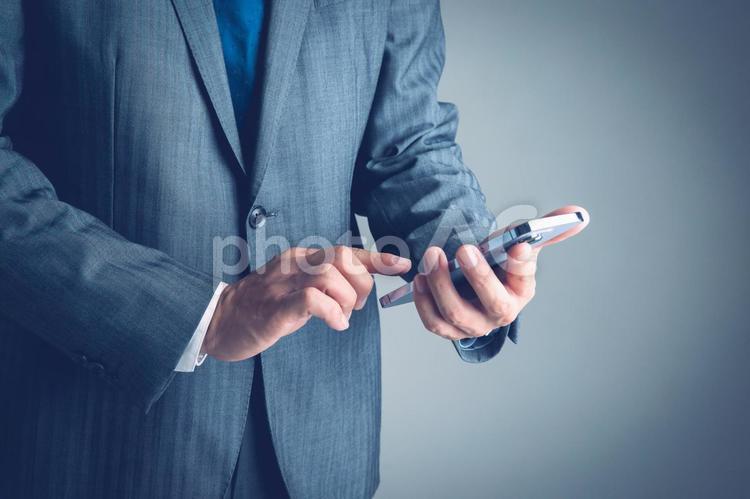 スマホを操作するビジネスマン 携帯電話,男性,スーツの写真素材