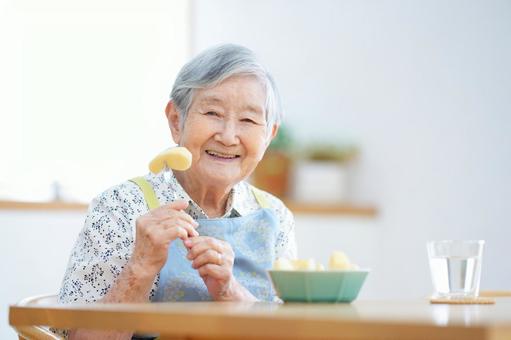 フォークに刺したリンゴを持つ笑顔の高齢女性 女性,リンゴ,フルーツの写真素材