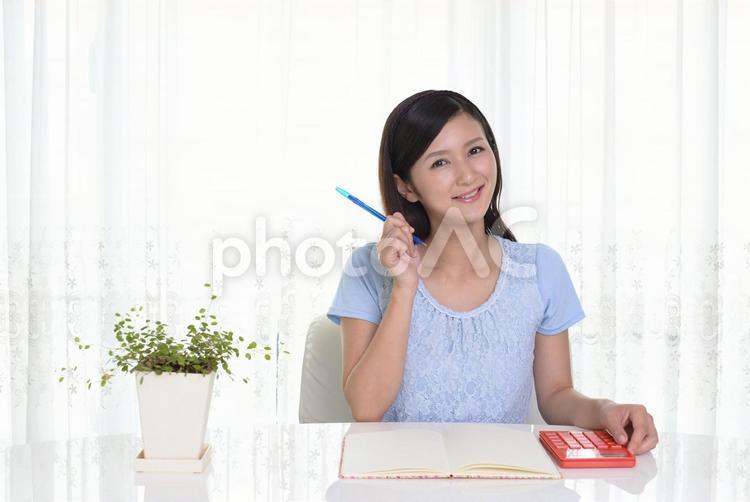 ノートと電卓を使う女性 女性,笑顔,ノートの写真素材